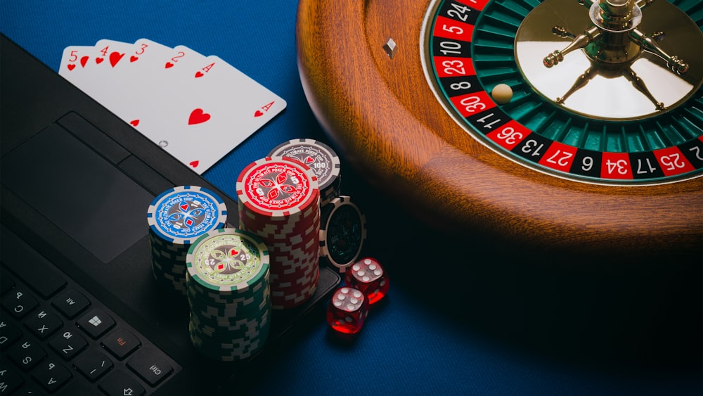 Roda roulette dan tumpukan chip warna-warni di atas meja kasino